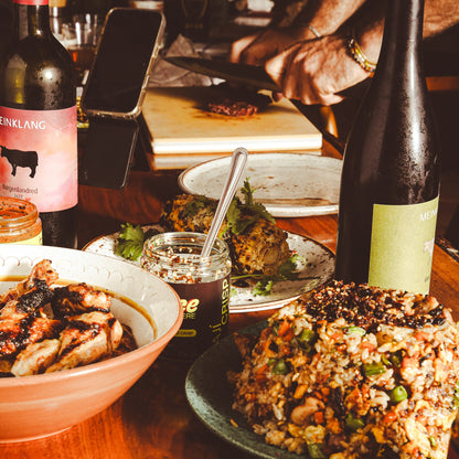 Plate of fried rice with chile sauce among dishes, jars, and bottles on dining table.