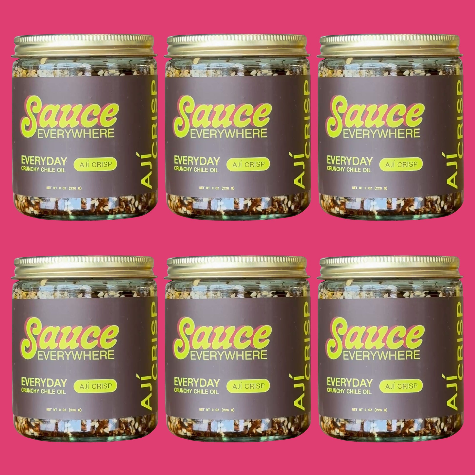 Six glass jars of Aji Crisp chile sauce by Sauce Everywhere against rose background.