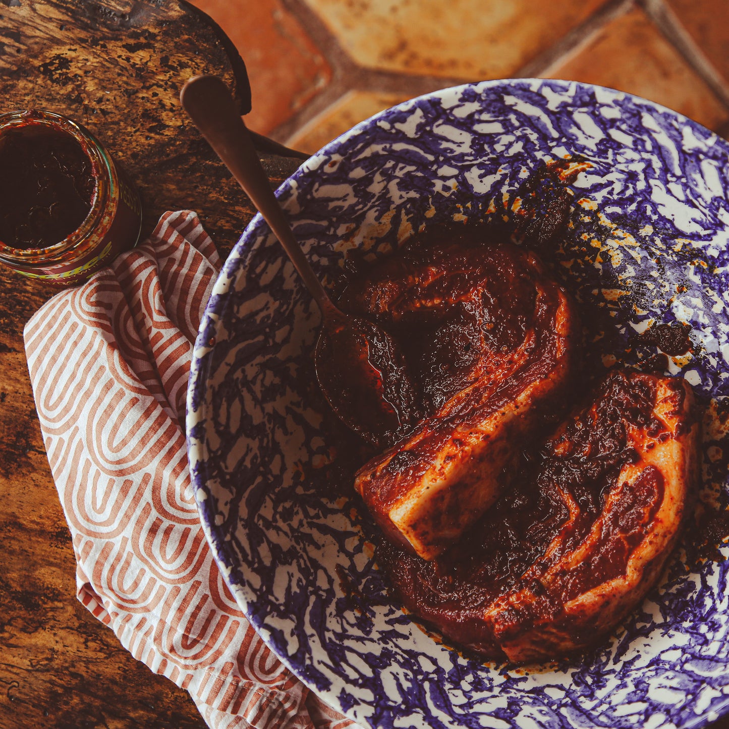 Pork chops marinated with chile sauce in mixing bowl on wooden table.